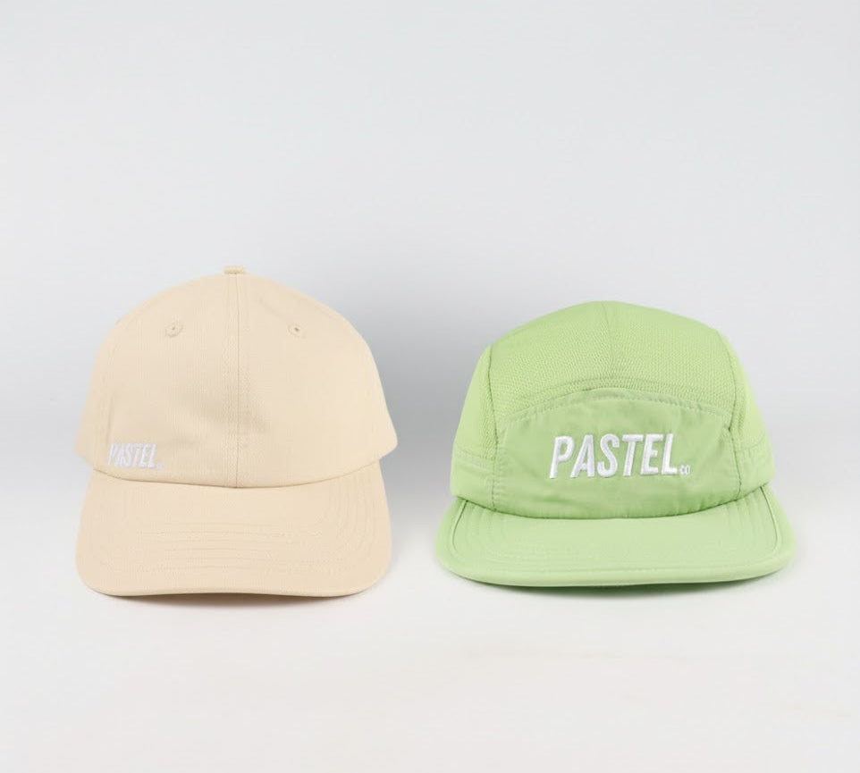 Two caps, one beige and one green, with 'PASTEL' branding on a light gray background.